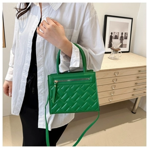 Detail of green quilted handbag with metallic zipper pocket and textured leather finish