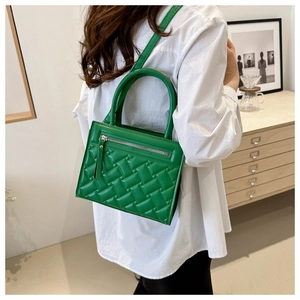 Detail view of emerald green quilted crossbody bag with stylish metallic zipper and handles