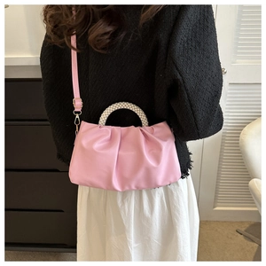 Detail of pink ruched cloud bag featuring decorative pearl bead handle and soft texture