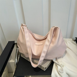 Light pink minimalist PU leather hobo tote bag with wide strap on a modern chair
