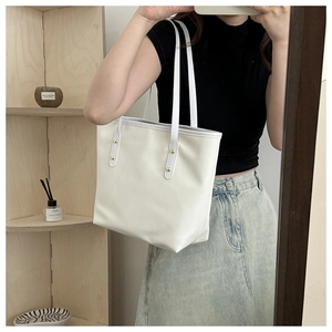 Close-up of minimalist beige PU leather tote bag with elegant gold rivet details on handles
