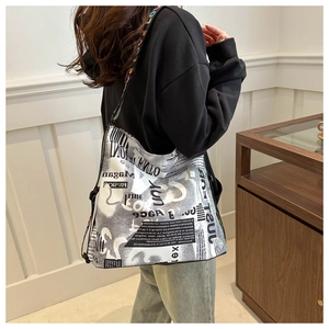 Détail du sac cabas en toile avec imprimé journal et bandoulière tissée colorée