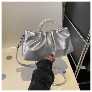 Detail of silver pleated cloud bag featuring a white pearl bead handle and smooth texture