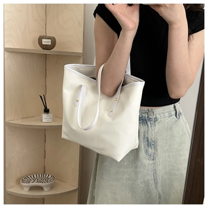 Close-up of cream tote bag with gold rivet details and premium stitching craftsmanship