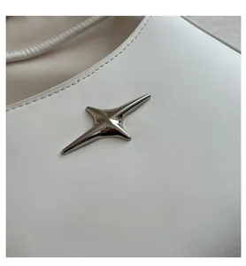 Detail of white leather shoulder bag with silver star hardware and neat stitching