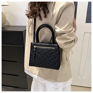 Detail of black quilted leather handbag with gold zipper and adjustable shoulder strap