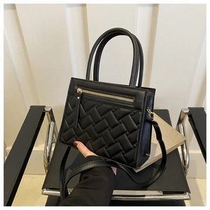 Detail of black textured handbag with lattice pattern and golden front zipper pocket
