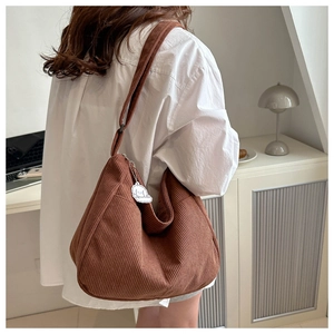 Close-up of brown corduroy hobo bag texture with a cute white puppy plush charm