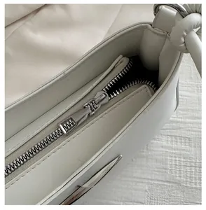 Close-up of smooth silver metal zipper on white minimalist PU leather shoulder bag