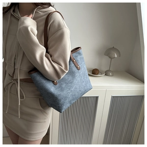 Detail of blue textured tote bag with brown leather straps and gold rivet accents