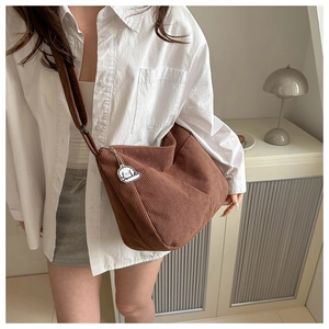 Detail of brown corduroy crescent bag with a cute white puppy charm accessory