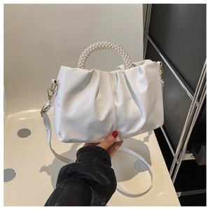 Detail of white ruched cloud bag featuring pearl-embellished handle and gold hardware