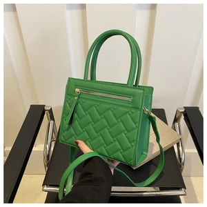 Close-up of emerald green quilted handbag with golden zipper and dual top handles