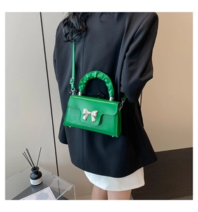Detail of green mini crossbody bag with silver bow accent and ruched cloud handle