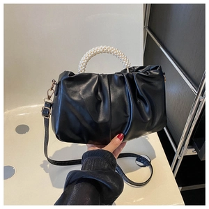 Detail of black pleated cloud bag featuring premium pearl handle and adjustable strap