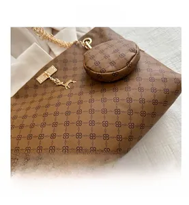 Detail of brown monogram tote bag with gold deer charm and chain strap accents
