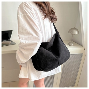 Model wearing large black corduroy tote bag in a home office setting, showing texture