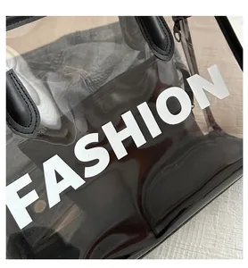 Close-up of black transparent PVC tote bag featuring white FASHION print and leather handles