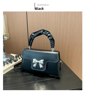 Detail of black mini handbag with silver metal bow and pleated scrunchie handle