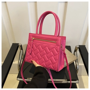 Detail of rose red quilted crossbody bag with front zipper and dual handles