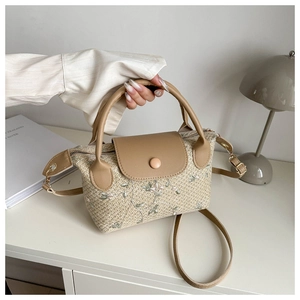 Détail d'un sac en paille d'été avec broderie florale et bandoulière en similicuir