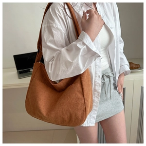 Close-up of caramel corduroy tote bag showing vertical texture and outer pocket on model