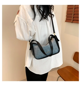 Detail van retro patchwork tas met blauwe denim stof en zwarte leren biezen