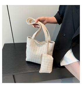 Detail of hand-woven beige straw tote bag with textured herringbone pattern and mini pouch