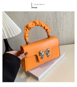 Detail of orange mini square bag with silver bow buckle and ruched handle design