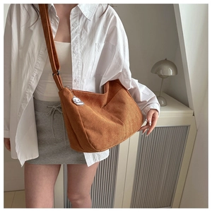 Brown corduroy crossbody bag shown with adjustable wide strap and white cloud charm accessory