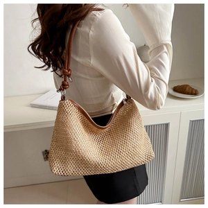Detail of woven straw tote bag with brown leather knotted straps and zipper closure
