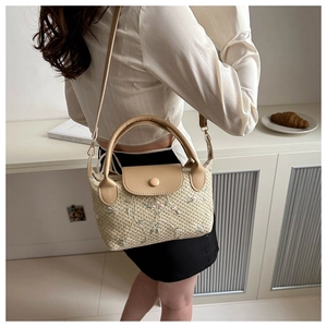 Gros plan sur la broderie florale du sac en paille avec poignée en cuir beige et rabat