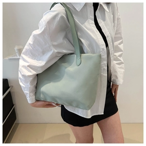 Mint green nylon tote bag shown from a side view on a model for size reference
