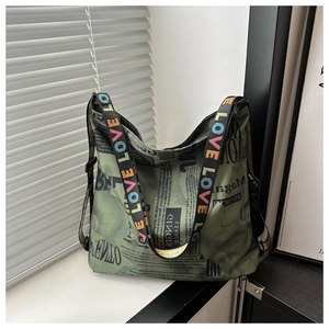 Vue détaillée de l'imprimé journal et de la sangle brodée LOVE sur le sac en toile vert