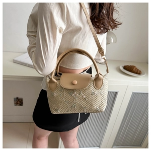Détail du sac en paille tissé à la main avec broderie florale et anse en similicuir brun