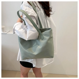 Detailed side view of light green tote bag being carried by a model for daily use