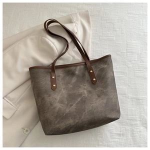Detailed overhead view of a large brown vintage tote bag with gold rivets on white fabric