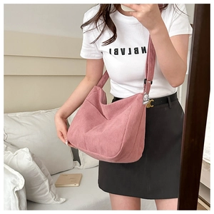 Close-up of pink corduroy dumpling bag with soft texture and cute dog pendant accessory