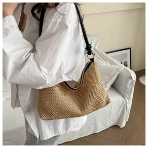 Detail of hand-woven straw underarm bag with black leather straps and knots