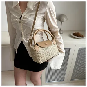 Detail showing white floral embroidery on woven straw and beige leather strap accents
