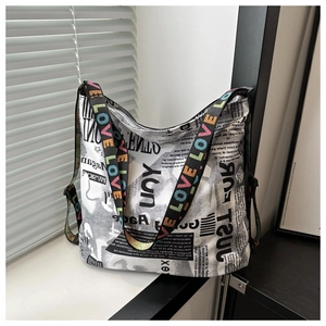 Détail d'un grand sac fourre-tout imprimé journal avec bandoulière à lettres LOVE