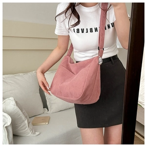 Detail of pink corduroy shoulder bag with cute doll charm and soft texture finish