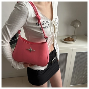 Detail of pink leather shoulder bag featuring silver star hardware and knotted strap design
