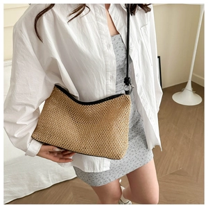 Close-up of woven straw shoulder bag with black trim detailing and natural fiber texture