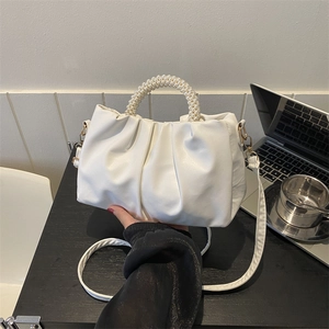 White ruched cloud bag with pearl handle and shoulder strap in a modern lifestyle setting