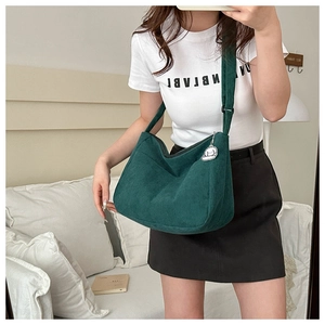 Deep green corduroy tote bag detail with wide shoulder strap and cute puppy pendant