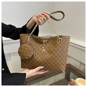 Detail of brown tote bag featuring geometric patterns, gold chain, and a deer charm