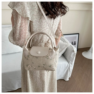 Close-up of beige woven mini bag with delicate floral embroidery and leather handle