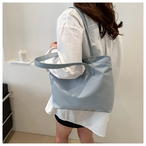 Detail view of large light blue nylon tote bag on shoulder with minimalist style
