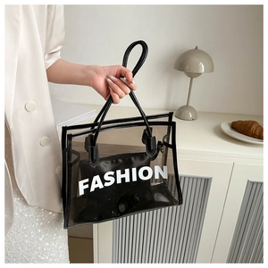 Detail of transparent PVC tote bag with black handles and fashion lettering in a lifestyle setting